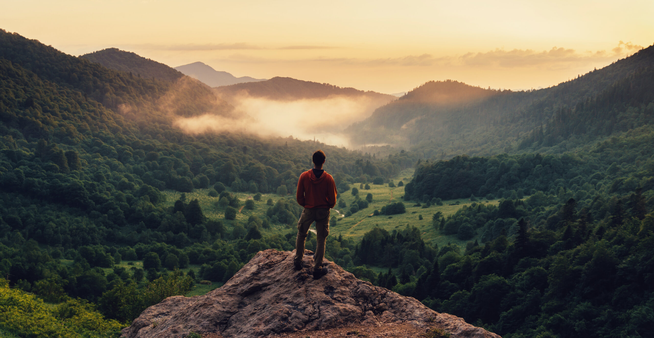 A person standing on a mountain top looking into the distance.
